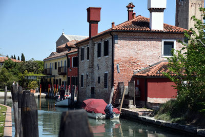 Canal amidst buildings against clear sky