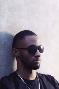 Portrait of young man wearing sunglasses against wall