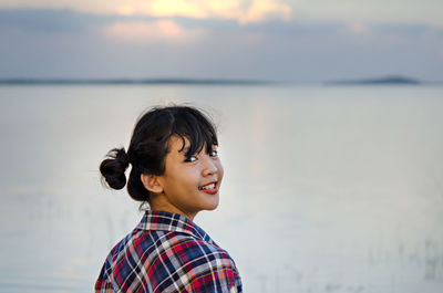 Portrait of smiling girl standing against sea