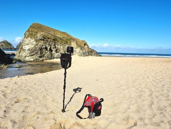 Man with umbrella on beach against blue sky