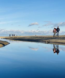 People on shore against blue sky