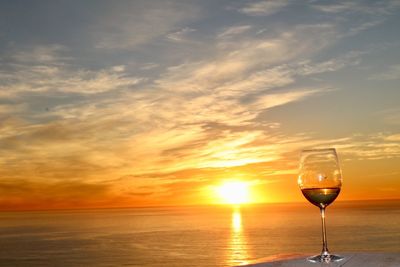 Close-up of beer in sea against sky during sunset