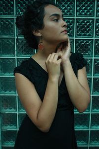 Young woman standing against frosted glass wall