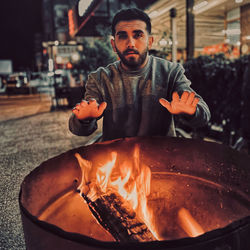 Portrait of young man preparing food in fire