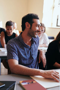 Young man smiling while looking away in language school