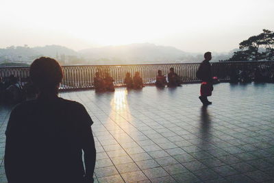 Rear view of silhouette people standing on bridge against sky