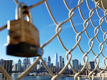 Urban skyline against sky seen through chainlink fence