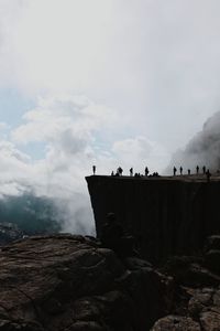 Low angle view of people on rock against sky