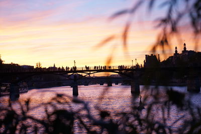 Silhouette bridge over river against sky during sunset