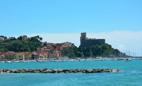 Buildings by sea against blue sky