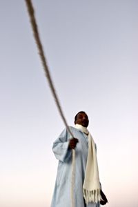 Low angle view of man standing on rope against sky