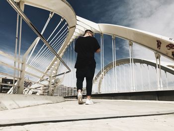 Man standing on footbridge against sky