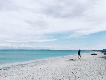 Man walking on beach against sky