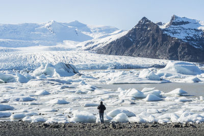 Rear view of man standing against frozen lake