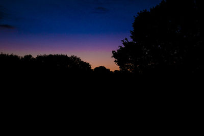 Silhouette of trees against sky at night