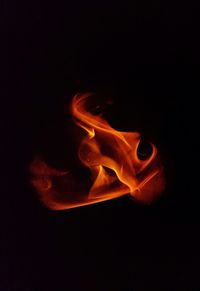 Close-up of burning candle against black background