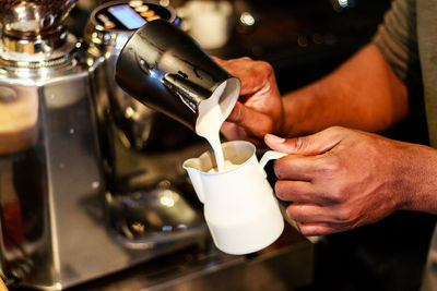 Close-up of hand pouring coffee in cafe