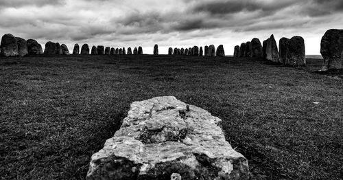 Rocks on field against cloudy sky