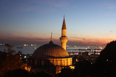 Mosque and cathedral in city against sky during sunset