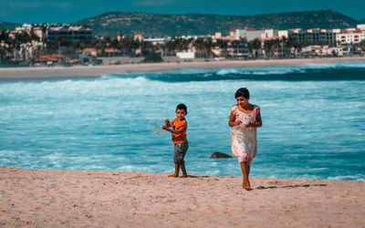 Full length of friends standing on beach