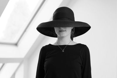 Portrait of woman wearing hat standing against wall