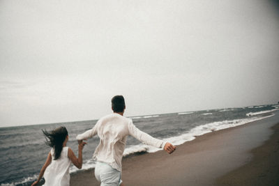 Rear view of people looking at sea against sky