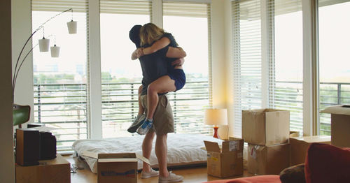 Couple embracing by window at home