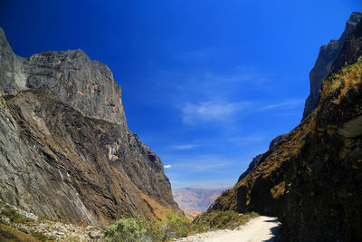 Road amidst mountains against blue sky 