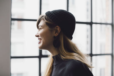 Smiling businesswoman looking through window at creative office