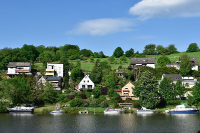 Houses by river and buildings against sky