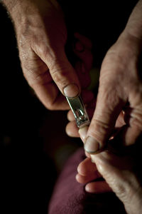 Man cutting fingernails of mother at home