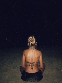Rear view of woman standing against black background