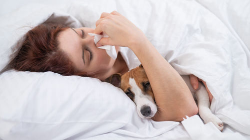 Woman with dog relaxing on bed at home