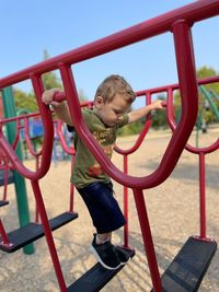 Young boy crossing playground bridge 