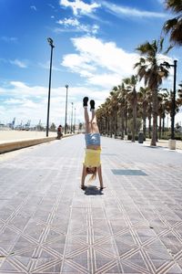 Girl doing handstand on footpath