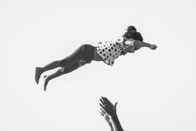 Low angle view of woman jumping against sky over white background