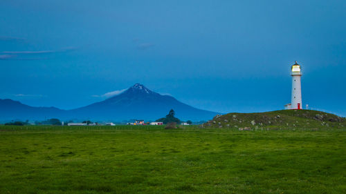 Lighthouse on field with mountain in background