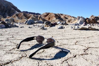 Sunglasses at death valley national park by hill against clear sky