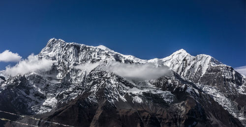 Scenic view of snowcapped mountains against blue sky