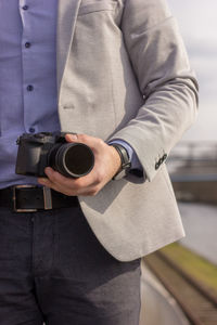 Midsection of man holding camera