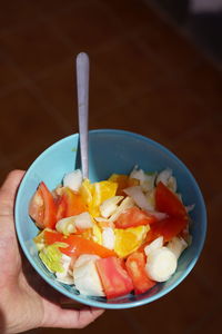 Close-up of hand holding fruit salad in bowl