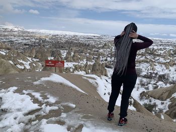 Man standing on snow covered landscape against sky