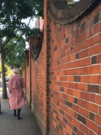 Rear view of woman walking on brick wall