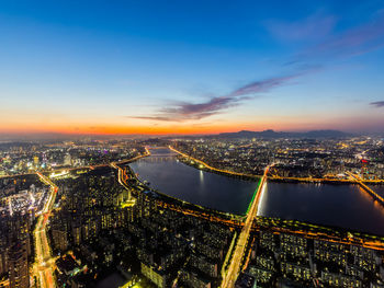 High angle view of illuminated city against sky during sunset