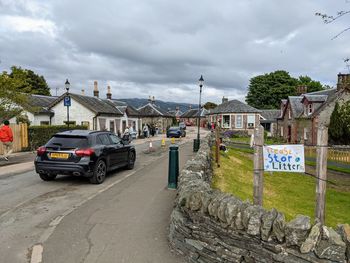 Cars on street by buildings against sky in city