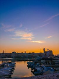 Boats moored at harbor against sky during sunset