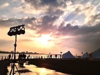 Silhouette people on beach against sky during sunset