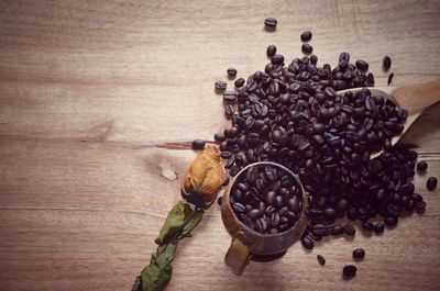 High angle view of coffee beans and wilted flower on table