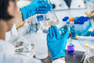 Midsection of scientist examining chemical in laboratory