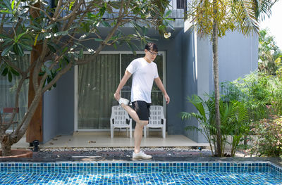 Full length of man standing by swimming pool against trees